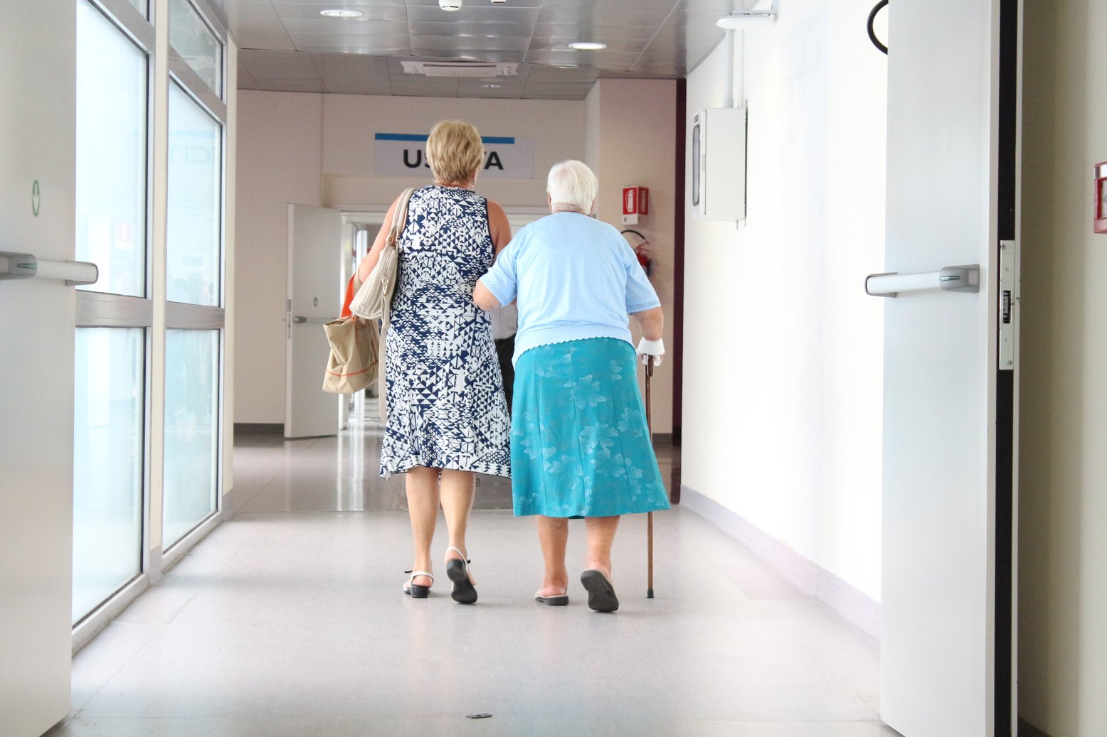 Adult Woman Walking with Her Senior Mother in the Hospital